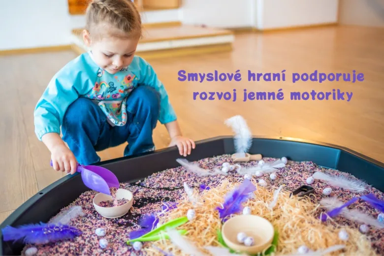 Dítě hraje s jemnou motorikou v hračičce plné písku a peří.