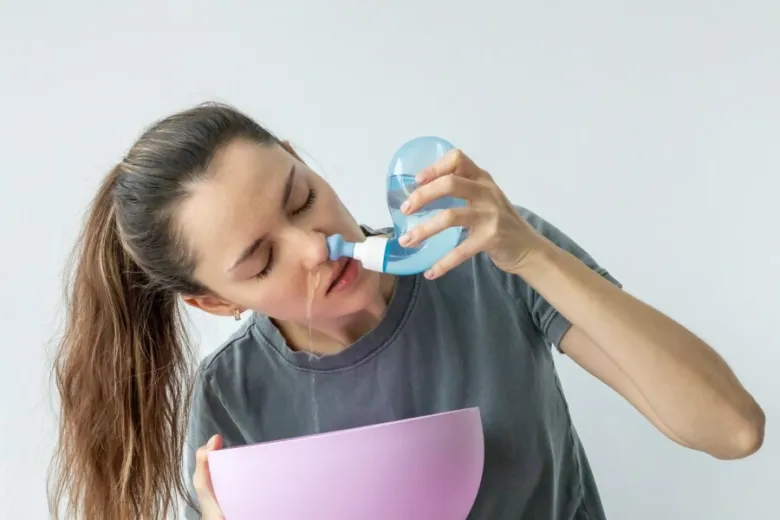Žena provádí mytí nosu solným roztokem do misky.