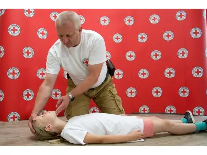 Instruktor první pomoci ukazuje dětem techniku resuscitace.