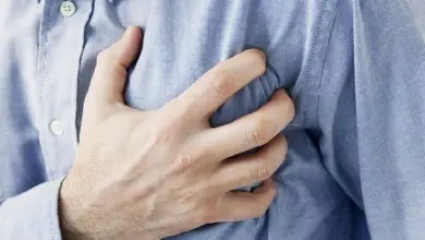 Muž drží ruku na hrudi kvůli bolesti.