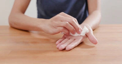 Dítě otírá dlaň ruky bílou vložkou nebo ubrouskem.