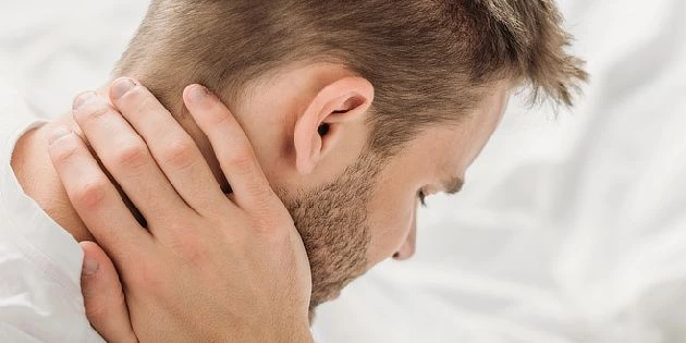 Muž drží krk v bolesti kvůli zánětu kloubů.