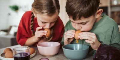 Děti foukají vejce do mise bez prasknutí.