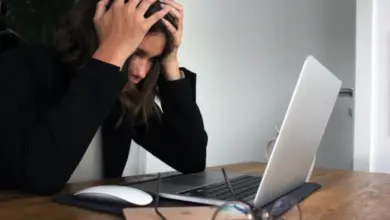 Žena sedí u počítače s bolestmi hlavy.