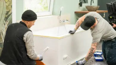 Muži natírají dlažbu v koupelně barvou na obklady.