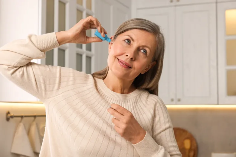 Žena vkládá modrý nástroj na čištění ucha do svého ucha.