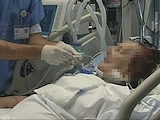Lékař provádí tracheostomii pacientovi v nemocničním lůžku.