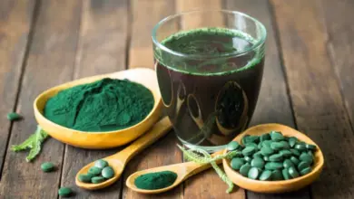 Sklenice s tekutou spirulinou vedle prášku a tablet.