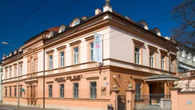 Historická budova s fasádou v pastelových barvách pod modrou oblohou.