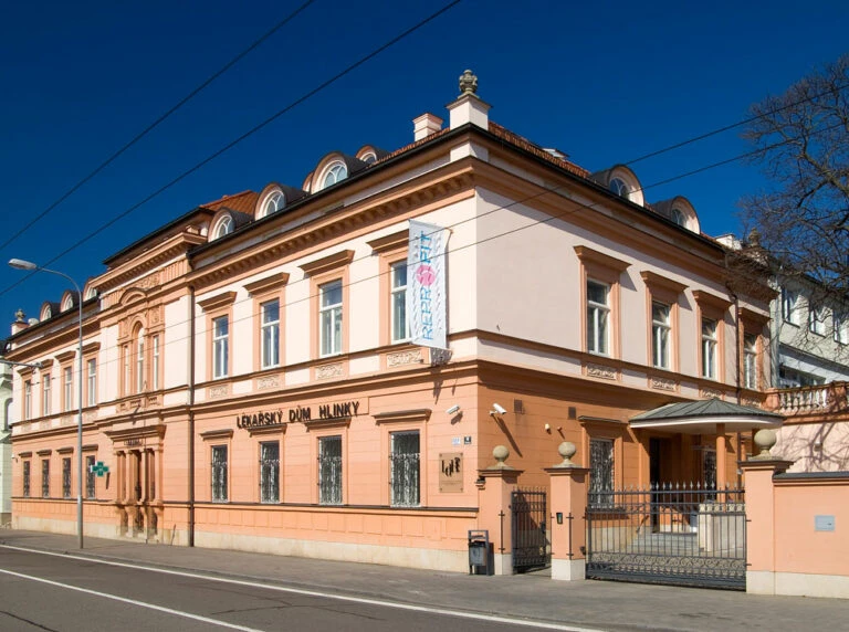 Historická budova s fasádou v pastelových barvách pod modrou oblohou.