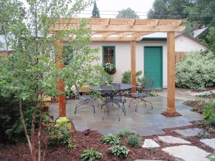 Hotová dřevěná zahradní pergola s venkovním nábytkem.