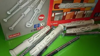 Bílé hmoždinky se šrouby v balení značky KLIMAX na zeleném povrchu.