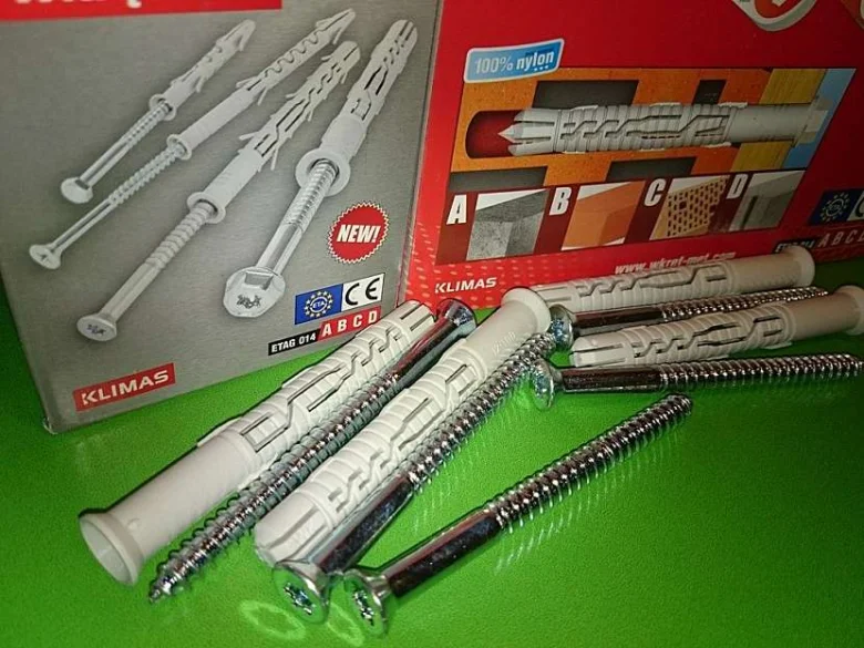 Bílé hmoždinky se šrouby v balení značky KLIMAX na zeleném povrchu.