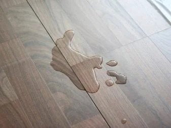 Voda rozlitá na laminátové podlaze ukazuje riziko poškození.