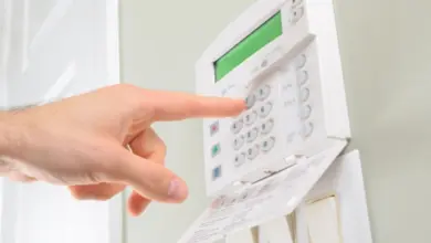 Ruka stiská tlačítka na bílém zabezpečovacím systému EZS/PZTS.