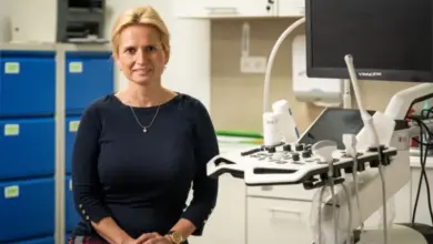 Žena sedí v ordinaci vedle ultrazvukového přístroje.