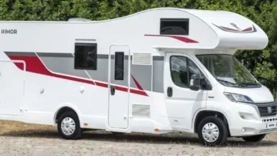 Bílý obytný vůz typu karavan zaparkovaný na štěrku.