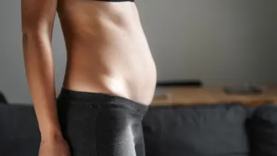 Žena s viditelně těhotným břichem v tmavých legínách.