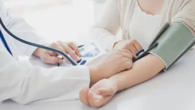 Lékař měří krevní tlak ženě pomocí automatického manometru.
