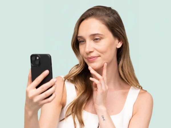 Žena se dívá na telefon s myšlenkou o péči po porodu.