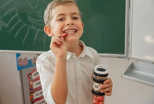 Chlapec drží sklenici s cukrářskými skořicovými bonbóny.