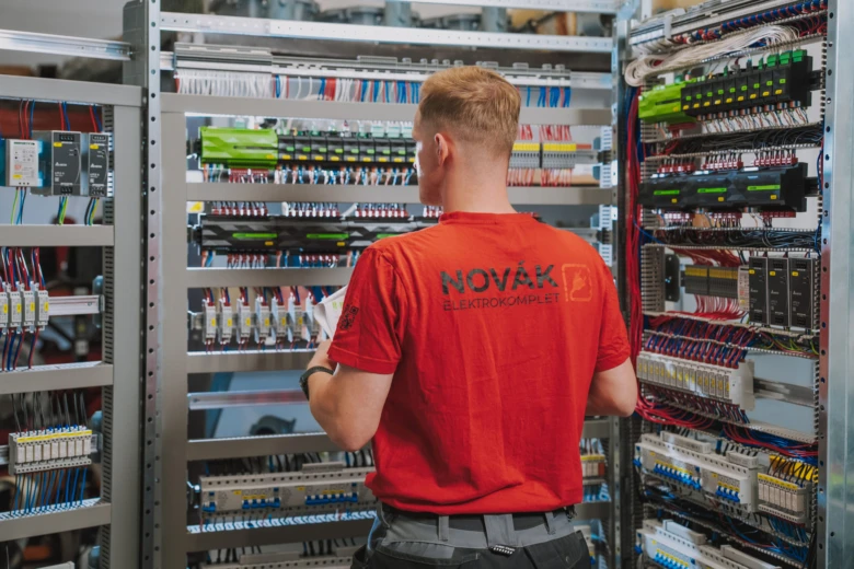 Elektroinženýr pracuje na rozvaděči s kabeláží a moduly.
