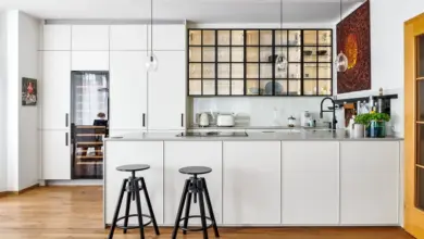 Bílý kuchyňský pult s černými židlemi a moderním designem.