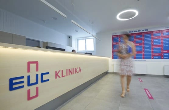 Žena chodí v recepci lékařské kliniky s logem EUC.