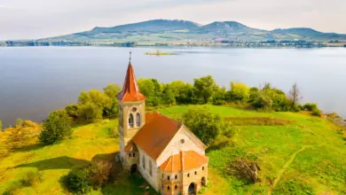 Starý kostel na kopci nad jezerem v krajině.