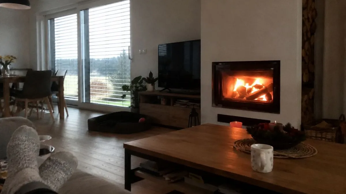 Vnitřní krb s hořícím dřevem v obývacím pokoji.