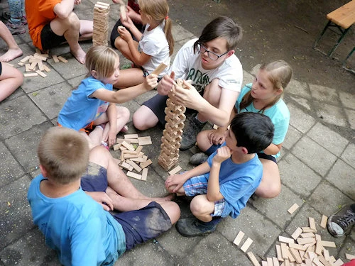 Děti hrají společně s dospelým v místnosti.