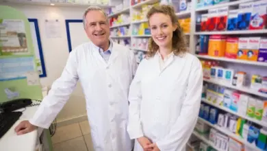 Dva farmaceuti v lékárně s řadami balení léků.