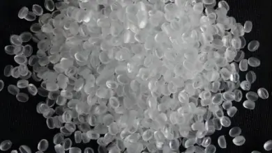 Bílá granulovaná plastová hmota polyethylen tereftalát na černém pozadí.