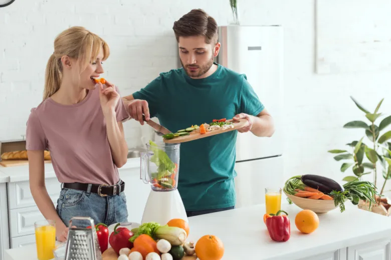 Muž i žena připravují zeleninový smoothie s čerstvými suroviny.