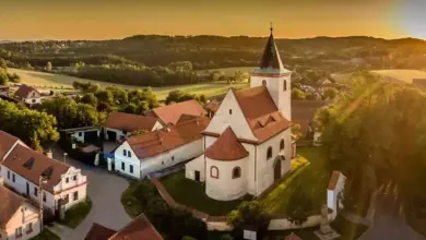 Kostel v vesnici při západu slunce s okolními domy.