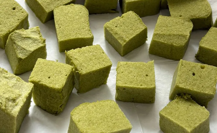 Kusky zeleného koláče s příchutí matcha na bílém podkladu.