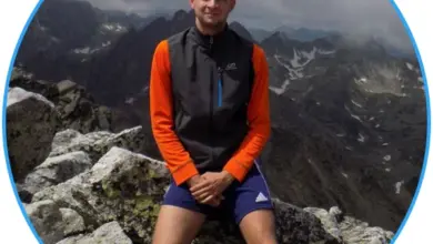 Muž sedící na horách v sportovním oblečení.