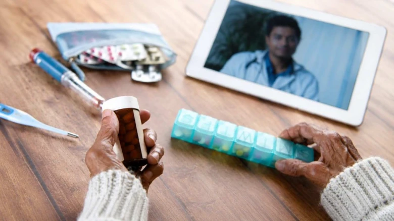 Starší osoba bere léky při videokonzultaci s lékařem na tabletu.