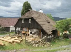 Starý dům z kmenů s dřevem na zahradě