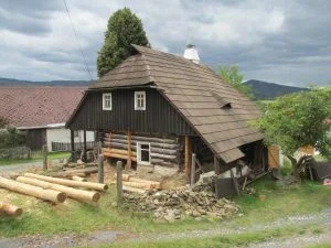 Starý dům z kmenů s dřevem na zahradě