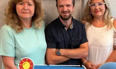 Tři lidé stojí vedle sebe s nápisy o zdraví a radosti.