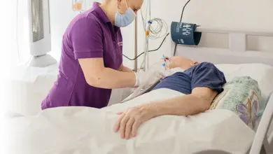 Sestra upravuje kyslíkový trubičku u pacienta v nemocničním lůžku.