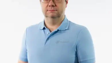 Muž v modrém tričku na bílém pozadí.
