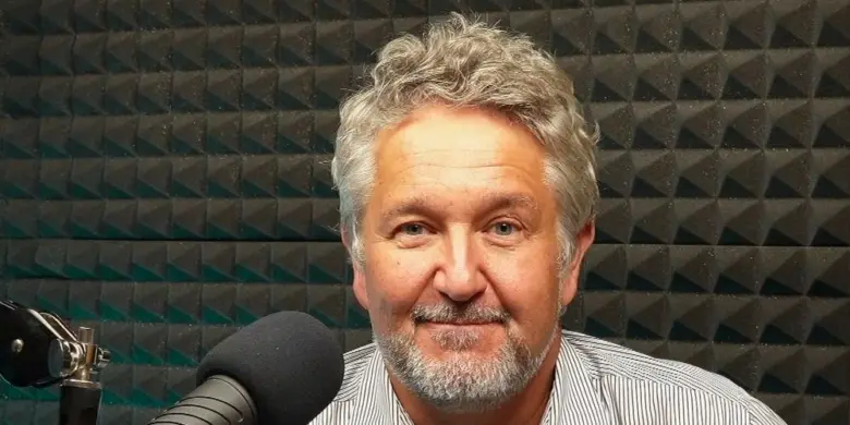 Muž s mikrofonem v nahrávacím studiu.