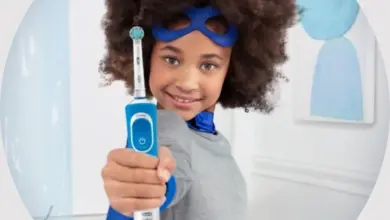 Dětský hrdina drží elektrický zubní kartáček v koupelně.