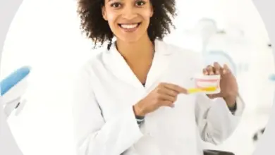 Žena v bílém plášti drží zubní model a ukazuje na něj.