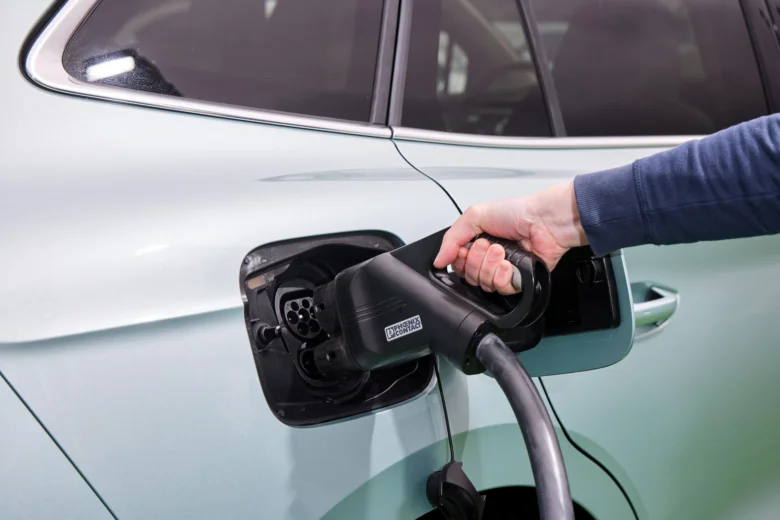 Osoba nabíjí elektromobil do zásuvky na boku vozu.