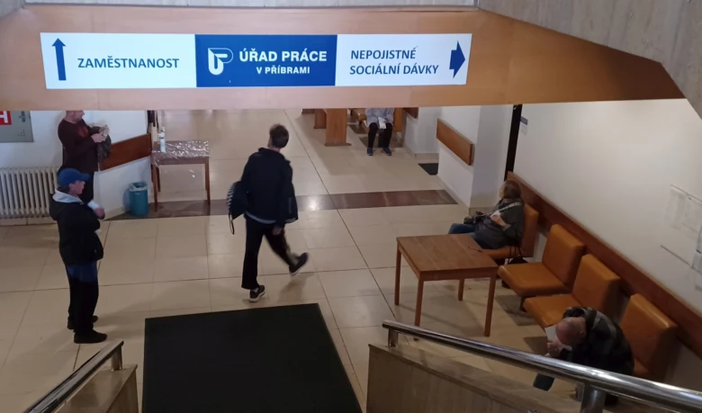 Lidé čekají v chodbě úřadu práce.