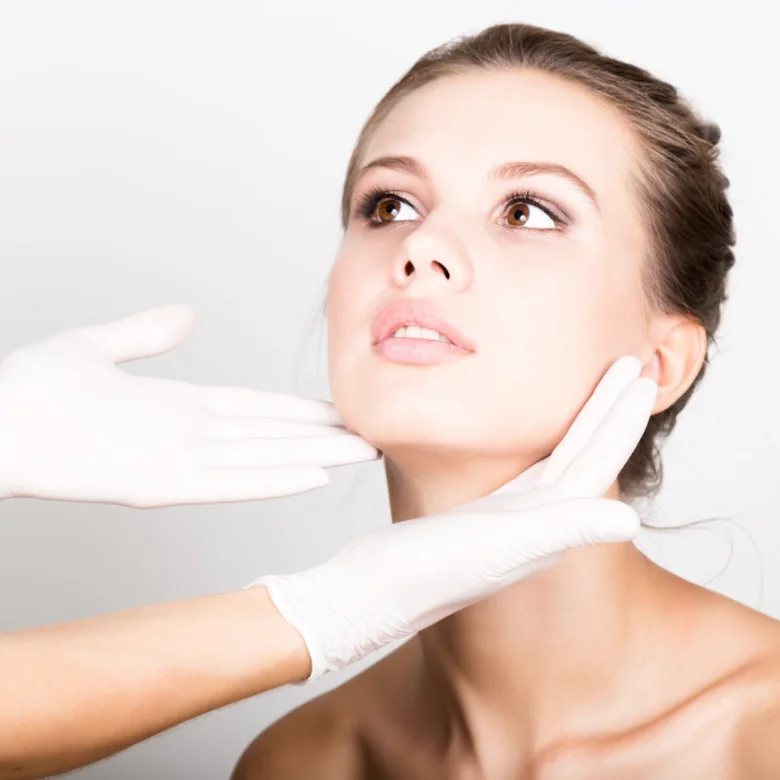 Žena s rukavicemi dotýká obličeje - ilustrační foto pro dermatologii.