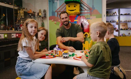 Rodina se hraje s kostkami LEGO v interiéru hřiště.